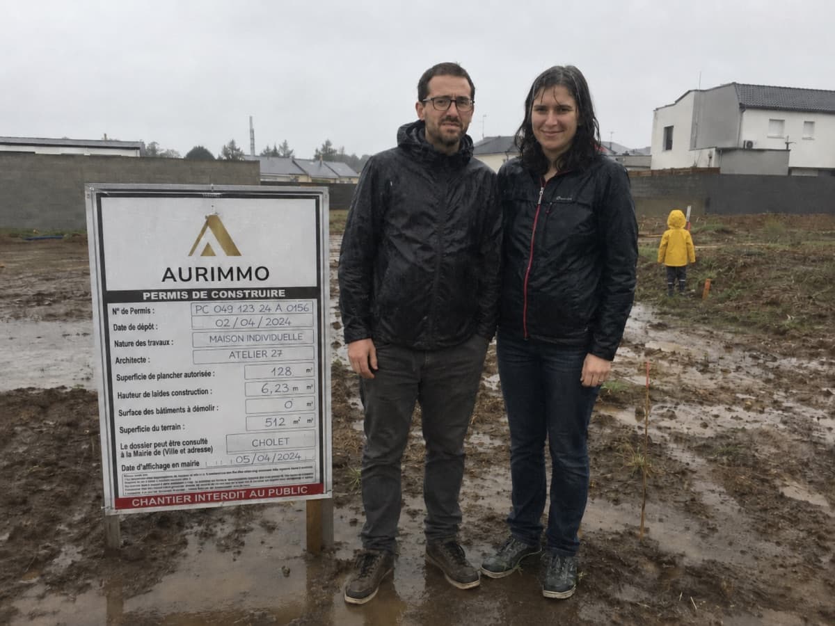 Pierre et Vanessa sur leur terrain avec leur panneau de permis de construire Aurimmo